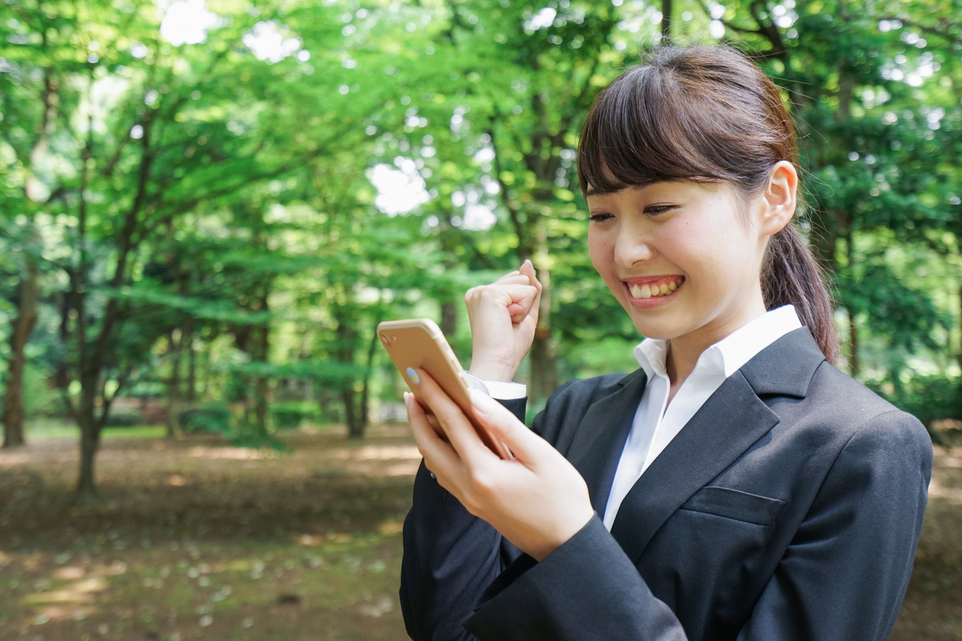 女性がスマホを見てガッツポーズをしている写真